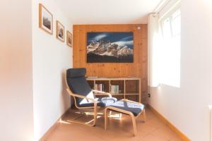 Una sala de estar con una silla y una estantería. en Dolomiti Garden Flat, en Villanova