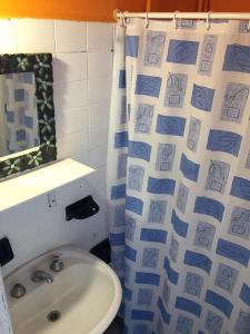 a bathroom with a sink and a shower curtain with drawings on it at La Vecindad del Sol Depto H in Miramar