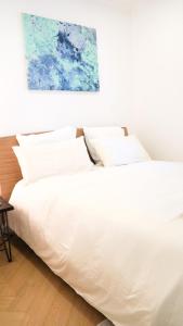 a white bed with white pillows in a bedroom at Kalumi Aparthotels - Japandi-Style Apartments with Terrace, Pergola, and Portuguese BBQ in Vila Nova de Milfontes