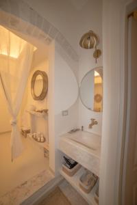 een witte badkamer met een wastafel en een spiegel bij PugliAlcove in Castellana Grotte