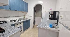 a white kitchen with blue cabinets and a refrigerator at Tres Playas Apartment in Puerto de Mazarrón +28 photos