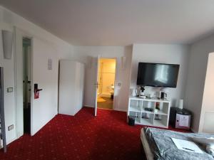 a room with a bed and a flat screen tv at Die Villa Hotel in Leverkusen