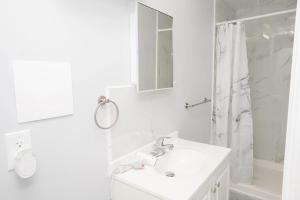 Un baño blanco con lavabo y ducha. en Brighton Beach Retreat Blue30, en Brooklyn