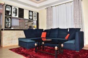 Una sala de estar con un sofá azul y una mesa. en Yukis & Kukis Place 5 Bedrooms, en Embu