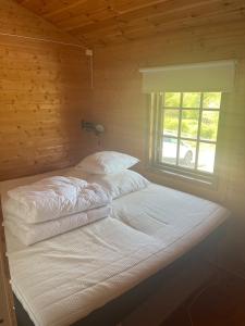 a bed with white sheets and a window in a room at Cottage by the lake in Namsos in Fosslandsosen