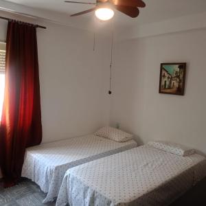 Un dormitorio con dos camas y un ventilador de techo. en Rooms Malaga, en Málaga