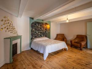 ein Schlafzimmer mit einem Bett, einem Kamin und einem Stuhl in der Unterkunft Maison auvergnate cœur de village in Messeix