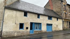 ein altes Steingebäude mit blauen Türen auf einer Straße in der Unterkunft Maison auvergnate cœur de village in Messeix