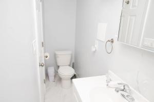 a white bathroom with a toilet and a mirror at Beachh - 2Beach House - Yellow3090 in Brooklyn +2 photos