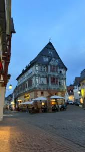 a large building on a street with tables and umbrellas at Hotel zum Riesen - älteste Fürstenherberge Deutschlands in Miltenberg