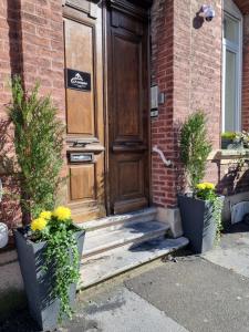 a wooden door of a house with two potted plants at Le Vauban Cambrai in Cambrai