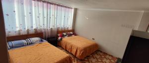 a bedroom with two beds and a window at Hostal Casa Blanca in Ayacucho