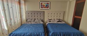a bedroom with two beds with blue sheets and aintendent at Hostal Casa Blanca in Ayacucho
