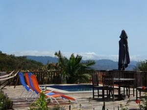 a pool with chairs and a table and an umbrella at Casa Domi in La Esperanza
