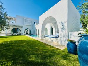 una grande casa bianca con un cortile con piscina di Charming Luxury Villa Poolside Paradise in Nature a Hammamet