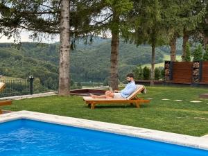 a man sitting in a chair next to a pool at Mountain House LISINSKA ROSA in Brdo +49 photos