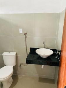 a bathroom with a white toilet and a sink at Recanto do Rancho Trancoso in Porto Seguro