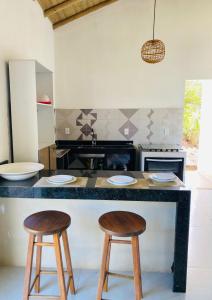 a kitchen with two wooden stools at a counter at Recanto do Rancho Trancoso in Porto Seguro +7 photos
