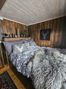 ein großes Bett in einem Zimmer mit Holzwänden in der Unterkunft Traditional cabin at Norefjell in Surteberg