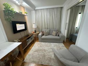 a living room with a couch and a tv at Hotel UH2107 Inter Jardins in São Paulo