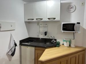 a small kitchen with a sink and a microwave at Hotel UH2107 Inter Jardins in São Paulo