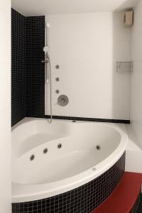 a white bath tub in a bathroom with black tiles at Marina Village in Herzliyya B +2 photos