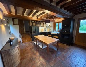 una cucina con tavolo in legno e una cucina con frigorifero di Charming house surrounded by nature a Courtonne-la-Meurdrac