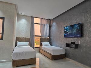 a bedroom with two beds and a tv on the wall at appartement moderne khenifra 2 in Khenifra
