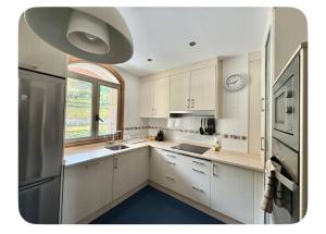 a kitchen with white cabinets and a clock on the wall at A Gandarela in Ribadavia