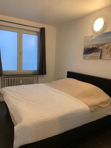 Un dormitorio con una cama blanca con una ventana. en Appartement Guillaume, en Blankenberge