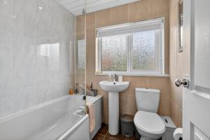 łazienka z toaletą, umywalką i oknem w obiekcie StayByNumbers - Spacious three bed house Royal Hillsborough w mieście Hillsborough +43 zdjęcia