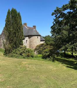 ein altes Steinhaus auf einem Feld mit Bäumen in der Unterkunft Splendide MANOIR - Proche plages - 4 chambres - 3sdb - 8 pers - WIFI in Plounérin