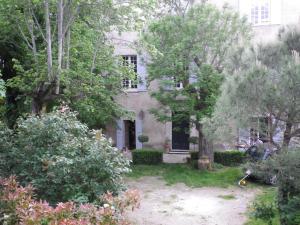 una casa vieja con árboles delante de ella en La Maison d'En Face, en Saint-Affrique-les-Montagnes