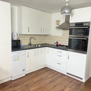 a kitchen with white cabinets and a sink at Newcastle No 30 Stay for Contractors, Families & Professionals in Heaton +6 photos