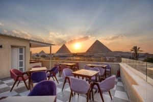 a patio with tables and chairs with pyramids in the background at AL Farida Boutique Pyramids in Cairo