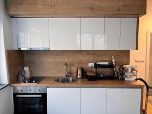 a kitchen with white cabinets and a sink at The New Wild Apartment apartman sa garaznim mjestom in Bjelašnica
