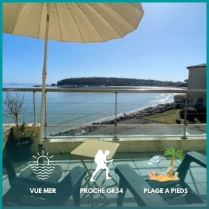 Una persona está parada bajo una sombrilla en un balcón. en Ty Jean - Piscine - plage à pied, en Crozon