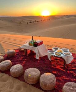 a table in the middle of the desert with food at Eternal Dunes Luxury Camp in Merzouga