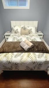 a bedroom with a bed with white sheets and leaves at Quiant 2 Bedroom Suite in Vancouver