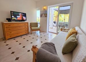 a living room with a couch and a tv on a dresser at Aldeamento Praia dos Beijinhos in Porches