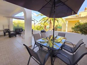 a table and chairs with an umbrella on a patio at Aldeamento Praia dos Beijinhos in Porches