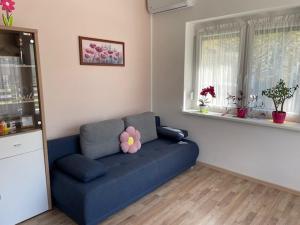 a living room with a blue couch with a flower on it at Két szobás, teraszos, kertes vendégház in Balatonmáriafürdő
