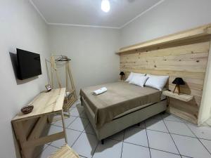 a bedroom with a large bed with a wooden headboard at Hotel Aconchegante in Jequié