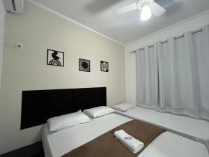a bedroom with two beds and a ceiling fan at Hotel Aconchegante in Jequié