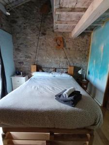 a bed in a room with a stone wall at Habitación Doble Cian Baño Privado Cartes in Cartes
