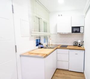 a kitchen with white cabinets and a wooden counter top at Pedrega Beach in Málaga