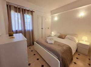 a white bedroom with a large bed and a window at Aldeamento Praia dos Beijinhos in Porches