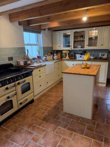 eine Küche mit weißen Schränken und einer Holzarbeitsplatte in der Unterkunft Buddleia Cottage Trewoon, St Austell in St Austell