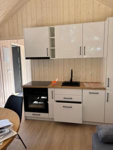 a kitchen with white cabinets and a stove top oven at Domki nad Krzyworzeką in Dobczyce +6 photos