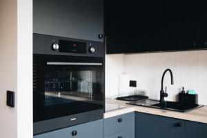 a kitchen with a black oven and a sink at Apartament WROTA DO PUSZCZY Z SAUNĄ in Hajnówka